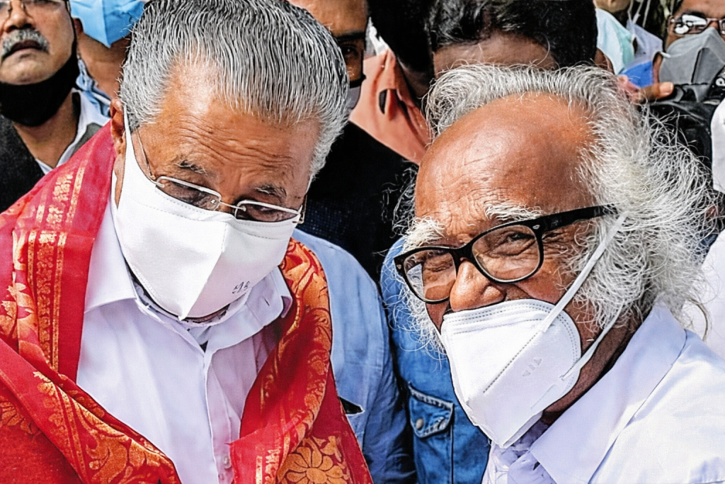Two men wearing face masks, one draped in a red shawl, engaged in conversation outdoors with a crowd in the background.